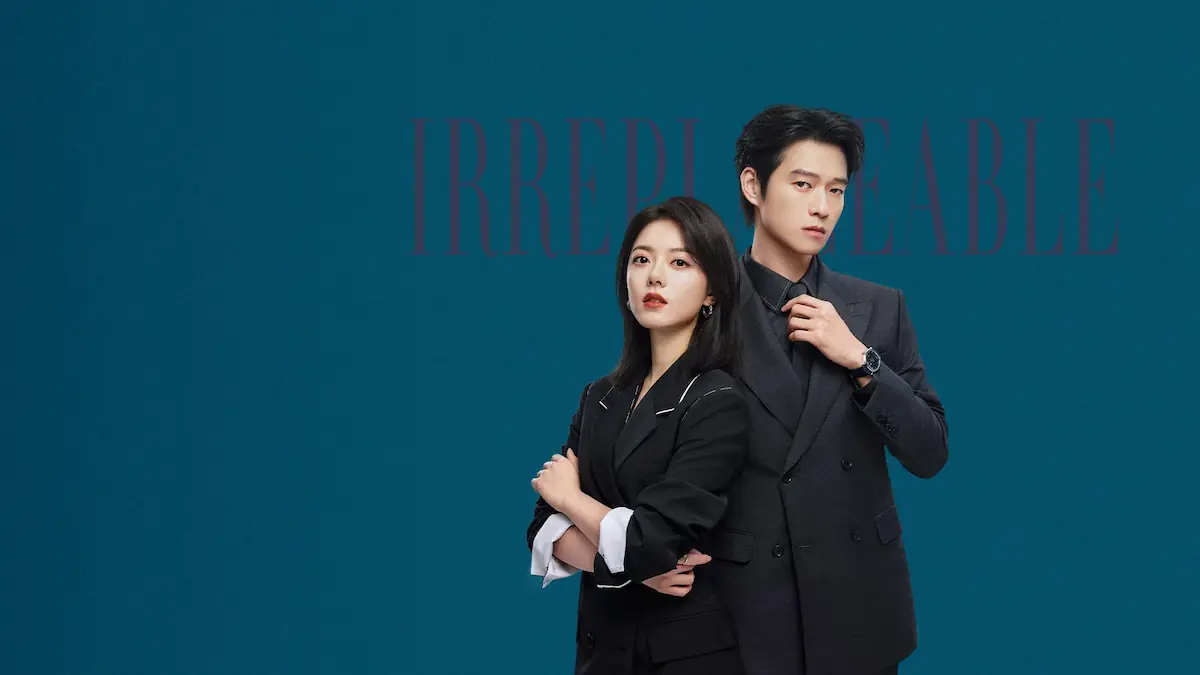 A sharp businessman adjusting his black tie next to an assertive businesswoman in a dark suit power-posing against a teal backdrop under title text reading Irreplaceable