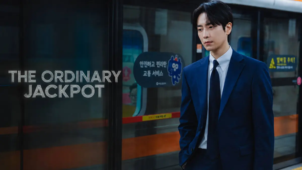 A man in a navy suit standing on a subway platform next to glass doors