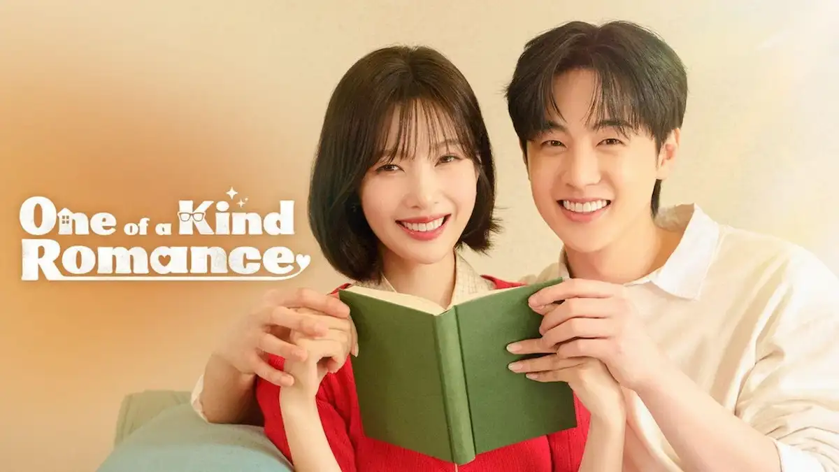A smiling young woman and a man holding an open green book together while sitting closely on a couch, featuring white and orange text reading One of a Kind Romance.
